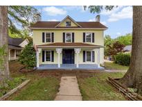 Charming two-story home with a yellow exterior, inviting front porch, and well-maintained landscaping at 522 Alexander St, Statesville, NC 28677