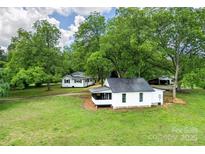 Aerial view of a quaint white home with mature trees on a lush green lawn at 615 & 625 Irish Potato Rd, Concord, NC 28025