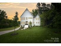 Stunning exterior of white home with lush green lawn, mature trees, and a driveway leading to the property at 621 Poindexter Dr, Charlotte, NC 28209
