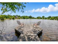 Beautiful waterfront view with a charming dock featuring chairs for relaxation, perfect for enjoying the serene lake at 7204 E 218 Hwy, Marshville, NC 28103