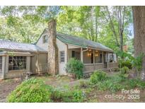 Charming home featuring a stone chimney, covered porch, and lush greenery at 749 N Miller Ave, Statesville, NC 28677