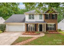 Charming two-story home featuring a brick and white facade, black shutters, and a well-manicured lawn at 8120 Vermilion Dr, Charlotte, NC 28215