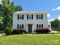 Charming two-story home with white siding, black shutters, a well-manicured lawn and mature landscaping at 10945 Wiltshire Ln, Charlotte, NC 28262