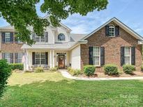 Charming two-story home with a well-manicured lawn and a welcoming front porch with black shutters at 1109 Woodwinds Dr, Waxhaw, NC 28173