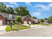 Charming brick townhomes feature attached garages, manicured lawns, and welcoming curb appeal at 121 Quality Dr, Mount Holly, NC 28120