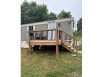 Exterior of home with new wooden deck and railings, side entry door, and gray siding at 4417 Grier St, Gastonia, NC 28056