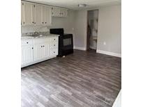 A cozy kitchen features white cabinets, laminate counter tops, and wood grain vinyl floors at 4417 Grier St, Gastonia, NC 28056