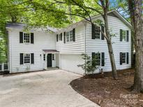 Charming two-story home featuring white siding, black shutters, and a paved driveway surrounded by lush greenery at 5016 Celeste Ct, Charlotte, NC 28270