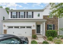 Charming two-story home featuring a white exterior, stone accents, and a two-car garage with landscaped front yard at 6726 Carradale Way, Charlotte, NC 28278