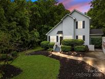 Charming two-story home with a well-manicured front yard, a lighted pathway, and lush landscaping at 7830 Sarah Dr, Denver, NC 28037