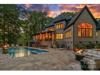 Luxury backyard features a pool, spa, and an outdoor seating area perfect for entertaining under a colorful sunset sky at 10300 Sweetleaf Pl, Charlotte, NC 28278