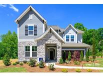 Charming two-story home featuring stone accents, gray siding, and a beautifully landscaped front yard under a clear blue sky at 11024 Shreveport Dr, Huntersville, NC 28078