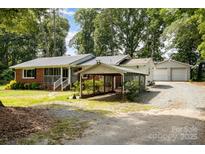 Charming brick home featuring a carport and detached garage, nestled amidst lush greenery and a spacious front yard at 2320 Doster Rd, Monroe, NC 28112