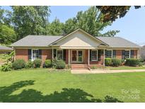 Charming brick ranch-style home with a well-manicured lawn and mature trees at 2443 Knickerbocker Dr, Charlotte, NC 28212