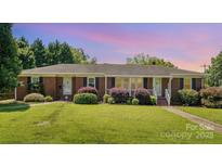 Charming one-story brick home with a lush green lawn and mature landscaping at 300 Caldwell St, Kannapolis, NC 28083