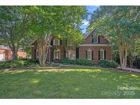 Charming brick home with lush landscaping and mature trees in a well-maintained front yard at 3506 Cardiff Ln, Matthews, NC 28104