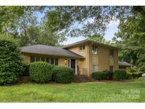 Traditional two-story brick home featuring mature trees, manicured shrubs and well-maintained lawn at 6017 Sierra Dr, Charlotte, NC 28216