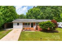 Charming single-story home featuring a cozy front porch and well-maintained lawn with mature shade trees at 613 Poplar Dr, Shelby, NC 28152