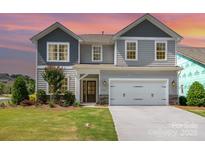 Charming two-story home featuring gray siding, a two-car garage, and a well-maintained front lawn at sunset at 7930 Rolling Wheels Rd, Charlotte, NC 28215