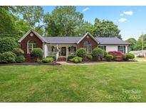 Charming brick and vinyl home with manicured lawn, lush landscaping, and inviting front porch at 1004 Gracebrook Dr, Salisbury, NC 28147