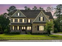 Charming two-story home featuring a stone facade, covered porch, and manicured lawn at 1008 Ladera Dr, Waxhaw, NC 28173