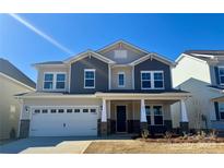 Charming two-story home with a welcoming front porch, a two-car garage, and beautiful architectural details at 1025 Puddle Pond Rd, Indian Trail, NC 28079