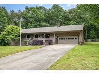 Charming single-story home featuring a front porch, attached garage, and a well-maintained lawn with mature trees at 1142 Foxberry Rd, Lincolnton, NC 28092