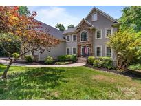 Stunning home showcasing a stone facade, manicured lawn, mature landscaping and a charming walkway leading to the front door at 2006 Sandy Pond Ln, Waxhaw, NC 28173