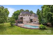 Stunning rear exterior view of home showcasing an in-ground pool and wooden deck, perfect for outdoor entertaining at 2006 Sandy Pond Ln, Waxhaw, NC 28173