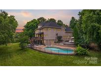 Stunning rear exterior view of a multi-story home featuring a pool, deck, and lush landscaping at 2006 Sandy Pond Ln, Waxhaw, NC 28173