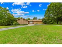 Lovely front yard with mature trees leads to a brick and stone house at 2309 Potter S Rd, Waxhaw, NC 28173