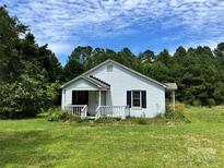 Quaint one-story white home with a covered porch, nestled amongst mature trees and lush landscaping at 2791 Neill Rd, Lancaster, SC 29720