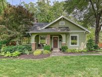 Charming green bungalow with a covered front porch, manicured lawn and mature landscaping at 3459 Selwyn Ave, Charlotte, NC 28209