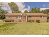 Charming brick home with a well-manicured lawn and mature landscaping at 5840 Potter Rd, Matthews, NC 28104