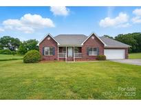 Charming red brick home boasts a well-manicured lawn and attached two car garage at 924 Secrest Hill Dr, Monroe, NC 28110