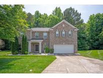 Charming two-story brick home with an attached two-car garage, manicured lawn, and lush landscaping at 10044 Markus Dr, Mint Hill, NC 28227