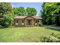 Charming brick home with a well-maintained lawn and inviting front porch nestled among mature trees at 110 Book Ct, Statesville, NC 28677