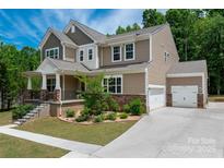 Charming two-story home with landscaped yard, stone accents, and a welcoming covered front porch at 13025 Cinnamon Fern Ln, Charlotte, NC 28227