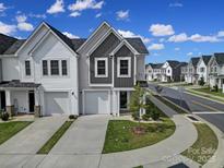 Modern townhome featuring attached garages and manicured front lawns on a sunny day at 149 Briana Marie Way, Indian Trail, NC 28079