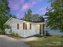 Charming single-story home with stone chimney, brown shutters, and lake views at sunset at 17835 Terryglass Ln, Charlotte, NC 28278