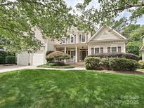 Inviting two-story home with lush landscaping, a front porch with rocking chairs, and attached two car garage at 2406 Tarleton Twins Ter, Charlotte, NC 28270