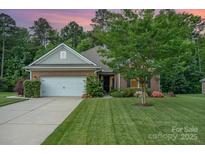 Charming brick home featuring a well-manicured lawn, mature tree, and inviting curb appeal at 8737 Mullis Forest Ct, Mint Hill, NC 28227