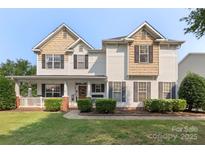Charming two-story home with a welcoming front porch and manicured landscaping at 9008 Magna Ln, Indian Trail, NC 28079