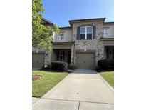 Charming townhome boasts a brick facade, attached garage, and manicured front yard with lush landscaping at 9593 Camberley Nw Ave, Concord, NC 28027