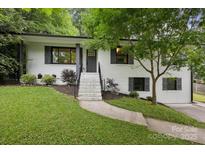 Charming white brick home with black accents and a welcoming front yard with mature tree at 1021 Nancy Dr, Charlotte, NC 28211