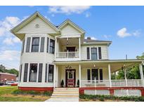 Charming two-story home showcasing a welcoming front porch, accented by red trim and black window shutters at 107 Hinton St, Chester, SC 29706