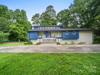 Striking blue two-story home with clerestory windows and gray brickwork, surrounded by mature trees at 1261 Westbrook Cir, Gastonia, NC 28052