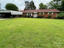 Charming single-story brick home featuring a lush green lawn and a convenient carport at 13427 Homewood Dr, Charlotte, NC 28262