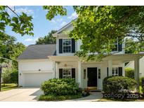 Charming two-story home features a covered front porch, lush landscaping, and an attached garage with basketball hoop at 16121 Wrights Ferry Rd, Charlotte, NC 28278