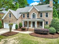 Charming brick home featuring a well-manicured lawn, covered porch, attached garage, and mature landscaping at 16714 Hammock Creek Pl, Charlotte, NC 28278